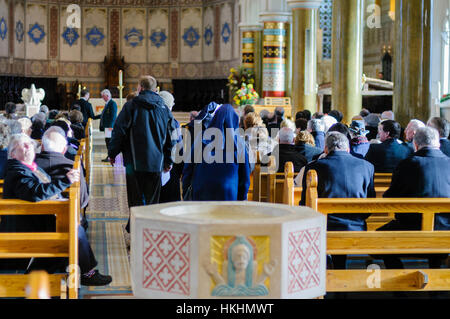 Menschen, darunter zwei Nonnen kommen in einer Kirche für eine Messe. Stockfoto