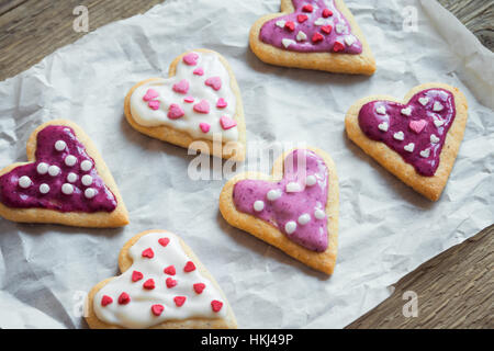 Herzförmige Cookies schließen für Valentinstag - selbstgemachter festlich dekorierten Kuchen Buiscuits Cookies auf Backpapier, Valentinstag Liebe Konzept Stockfoto