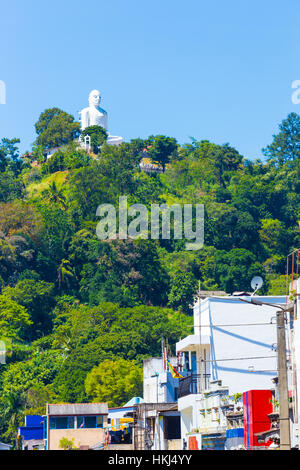 Fernen, weiße Bahiravokanda Vihara Buddhastatue auf Straße oder Boden von unten gesehen liegt auf einem Hügel in Kandy Stockfoto