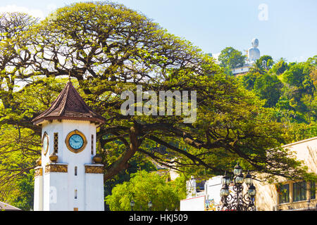 Ferne Bahiravokanda Vihara Buddha Statue gesehen über der Innenstadt von Kandy Glockenturm, ein Wahrzeichen der Stadt in Sri Lanka Stockfoto