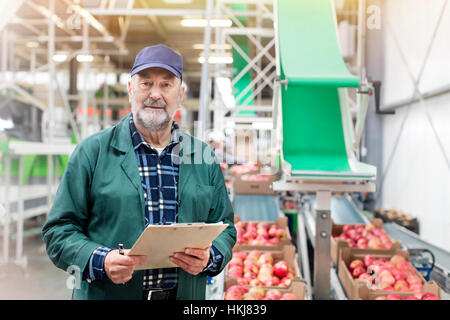 Porträt zuversichtlich Manager mit Zwischenablage in Apfel essen Aufbereitungsanlage Stockfoto