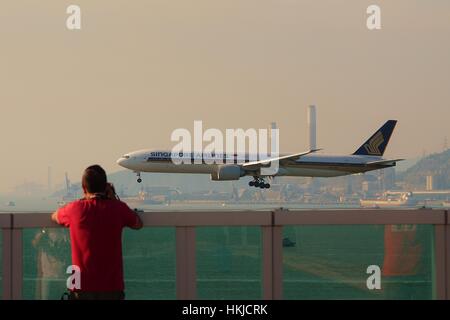 Ein Planespotter nimmt Foto von Singapore Airlines Boeing 777-300ER 9V-SWF-Landung am Hong Kong International Airport Stockfoto