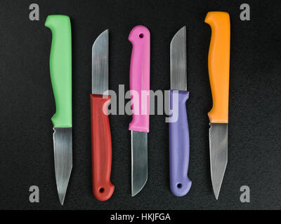 Reihe von bunten Küchenmesser vor schwarzem Hintergrund Stockfoto