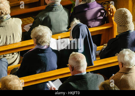 Menschen, darunter zwei Nonnen sitzen auf Bänken in einer Kirche für eine Messe. Stockfoto