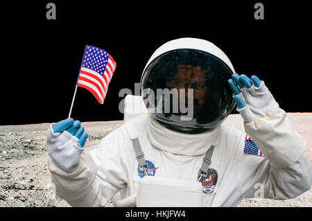 Person gekleidet wie ein NASA-Astronaut Holding eine amerikanische Flagge auf einer Straße. Stockfoto