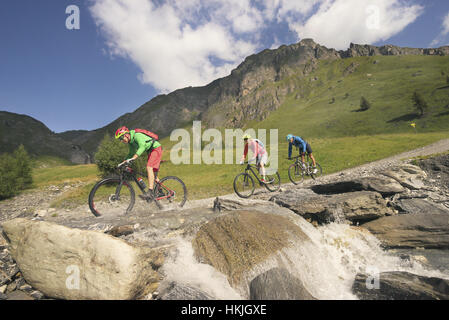 Drei Mountainbiker über Bach am Berg, Zillertal, Tirol, Österreich Stockfoto