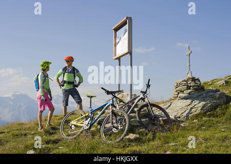 Junges Paar Mountainbiker gerade Infotafel weiter bergan, Zillertal, Tirol, Österreich Stockfoto