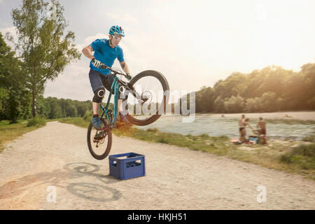 Mann springt mit Mountainbike über Bier Kiste, Bayern, Deutschland Stockfoto