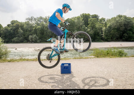 Mann springt mit Mountainbike über Bier Kiste, Bayern, Deutschland Stockfoto