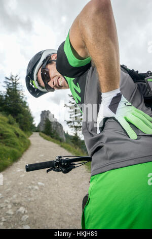 Mountainbiker mit Schmerzen im Rücken, Kampenwand, Bayern, Deutschland Stockfoto