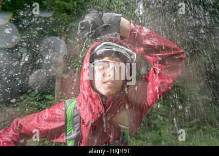 Mountainbiker stehen im Regen mit der Hand über den Kopf, Kampenwand, Bayern, Deutschland Stockfoto