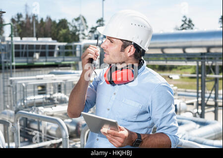 Männliche Ingenieur im Gespräch mit Walkie-talkie im geothermischen Kraftwerk, Bayern, Deutschland Stockfoto