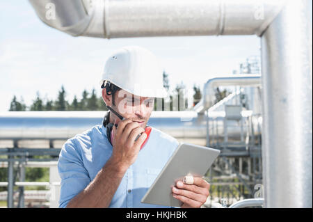 Männliche Ingenieur im Gespräch mit Walkie-talkie im geothermischen Kraftwerk, Bayern, Deutschland Stockfoto