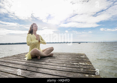 Frau beim Lotus Pose Yoga auf Steg am See, Ammersee, Oberbayern, Deutschland Stockfoto