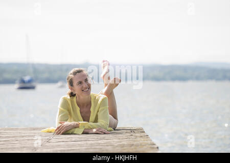 Nachdenkliche Frau ruht auf der Promenade am See, Ammersee, Oberbayern, Deutschland Stockfoto