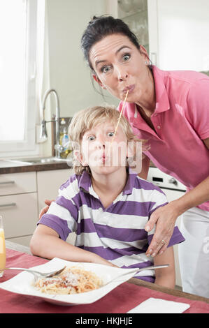 Porträt einer Frau mit ihrem Sohn Essen Spaghetti auf lustige Weise, Bayern, Deutschland Stockfoto