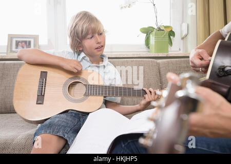 Frau mit ihrem Sohn Gitarrespielen in Wohnzimmer, Bayern, Deutschland Stockfoto