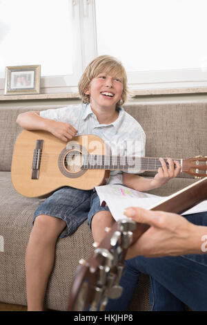 Frau mit ihrem Sohn Gitarrespielen in Wohnzimmer, Bayern, Deutschland Stockfoto