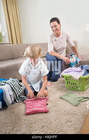 Frau mit ihrem Sohn Faltung Wäsche im Wohnzimmer, Bayern, Deutschland Stockfoto