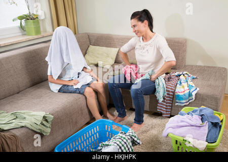 Frau mit ihrem Sohn Faltung Wäsche im Wohnzimmer, Bayern, Deutschland Stockfoto