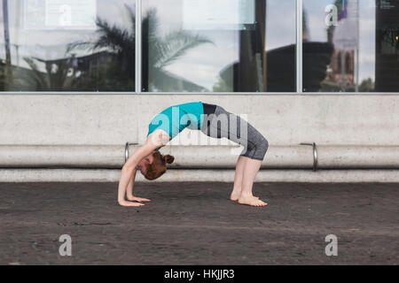 Junge Frau tut Brücke Pose auf Straße in Großstadt, Freiburg Im Breisgau, Baden-Württemberg, Deutschland Stockfoto