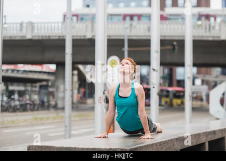 Junge Frau tut Kobra-Pose in Großstadt, Freiburg Im Breisgau, Baden-Württemberg, Deutschland Stockfoto