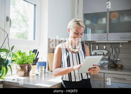 Junge Frau mit digital-Tablette in der Küche, Bayern, Deutschland Stockfoto