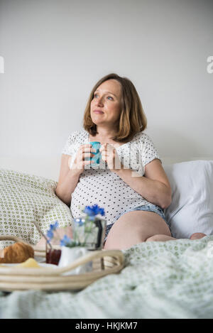 Schwangere Frau mit Frühstück im Bett, München, Bayern, Deutschland Stockfoto