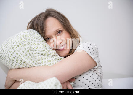 Glücklich schwanger Frau kuscheln ihr Kissen im Bett, München, Bayern, Deutschland Stockfoto