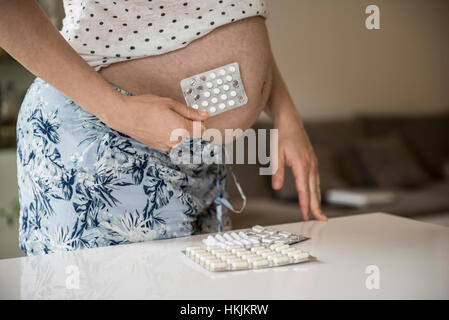 Mittelteil einer schwangeren Frau mit Blisterpackung vor Bauch, Munich, Bavaria, Germany Stockfoto