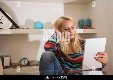 Schöne junge Frau, die mit digital-Tablette in die Wohnzimmer, Bayern, Deutschland Stockfoto