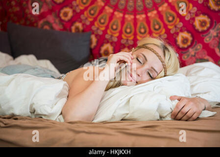 Schöne junge Frau am Smartphone in das Schlafzimmer, Bayern, Deutschland Stockfoto