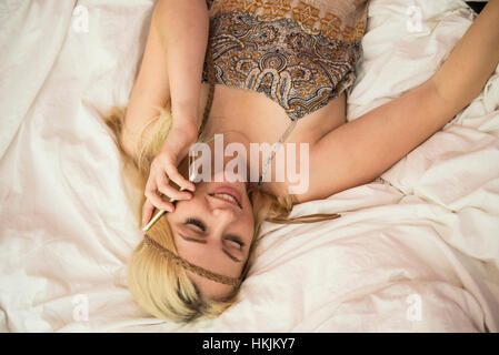 Schöne junge Frau am Smartphone in das Schlafzimmer, Bayern, Deutschland Stockfoto