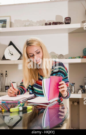Junge Studentin, die Hausaufgaben im Wohnzimmer, Bayern, Deutschland Stockfoto