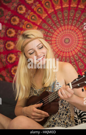 Junge Frau spielt Ukulele in das Schlafzimmer, Bayern, Deutschland Stockfoto