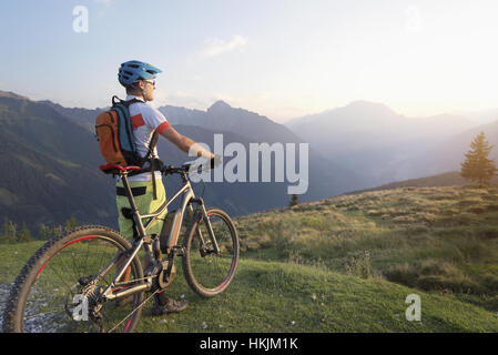 Rückansicht der Mountainbiker in die alpine Landschaft stehen und betrachten während Sonnenuntergang, Zillertal, Tirol, Österreich Stockfoto