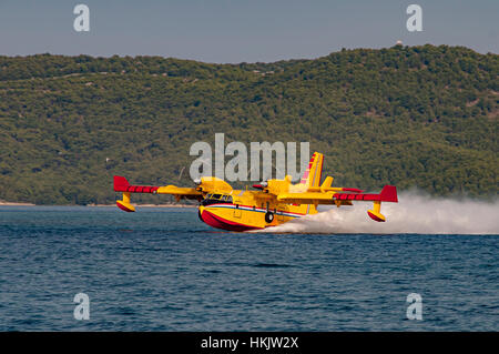 Gelbe und rote Canadair Wasser Bomber, Turbo prop Feuerwehr Flugzeug in Aktion, Wasser schöpfen Stockfoto