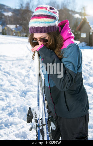 Mädchen lacht und hält ein paar Ski im Freien im Schnee Stockfoto