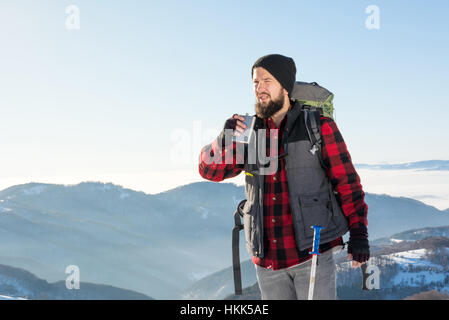 Mann trinkt aus einem Flachmann auf Winter-Wanderung Stockfoto