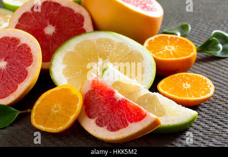 Zitrusfrucht-Sammlung von geschnittenen Grapefruits und Mandarinen auf einem Stein grauen Hintergrund. Früchte-Hintergrund-Essen. Gesunde Ernährung und Diät. Stockfoto