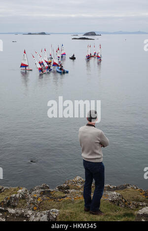 Mann beobachtet Topper Segeln Jollen während des Trainings, North Berwick Stockfoto