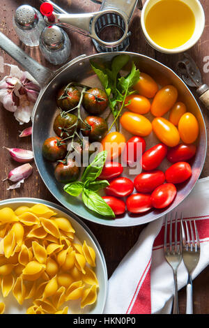 Zutaten für Pasta-Salat. bunte Tomaten, Zwiebel, Knoblauch, Auberginen, Olivenöl. Pasta shells.on einem alten Holztisch Stockfoto