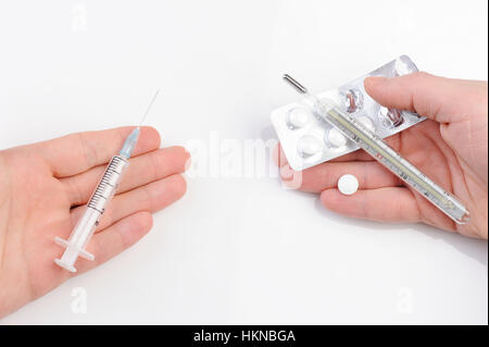 Thermometer, Spritze und Pillen auf Händen auf weiß Stockfoto