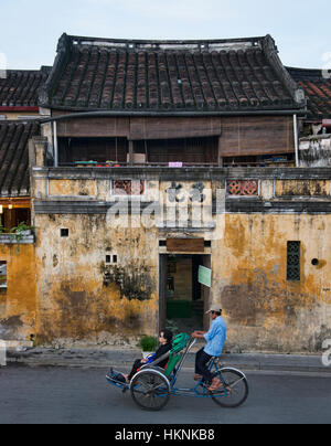 Cyclo-Fahrer und gelb Wände in der malerischen alten Stadt von Hoi an, Vietnam Stockfoto