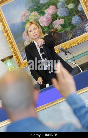 blonde Frau Auktionator Zeigefinger an Bieter Stockfoto