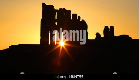 Die Sonne geht über Tynemouth Priory auf die an der Nordost-Küste. Stockfoto