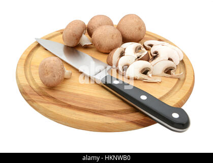 Messer mit in Scheiben geschnittenen und ganze Kastanie Pilze auf ein Schneidbrett aus Holz, auf einem weißen Hintergrund isoliert Stockfoto