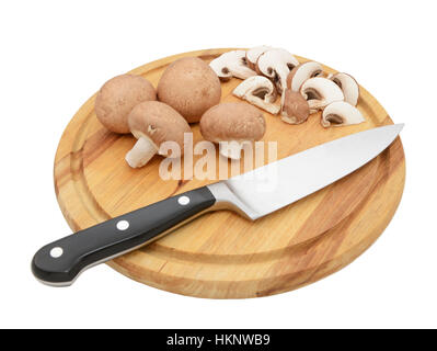 Scharfes Messer mit ganzen Kastanien Pilze und Scheiben auf einem kreisförmigen Schneidbrett aus Holz, auf einem weißen Hintergrund isoliert Stockfoto