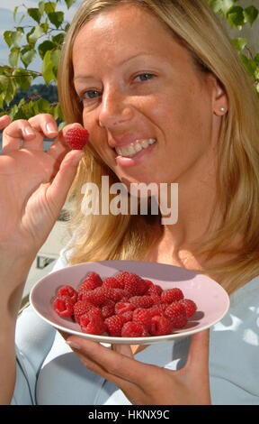 Frau isst Himbeeren Stockfoto