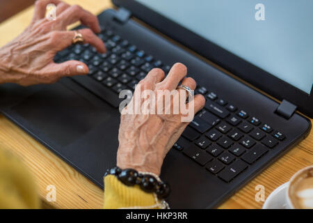 Alte Frau Hände und Laptop. Stockfoto